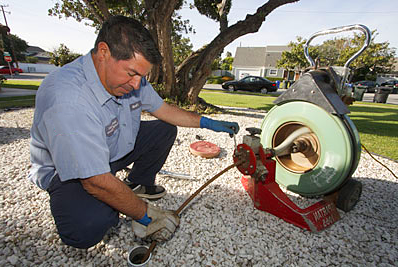 Sacramento plumbing team memeber power auguring a drain